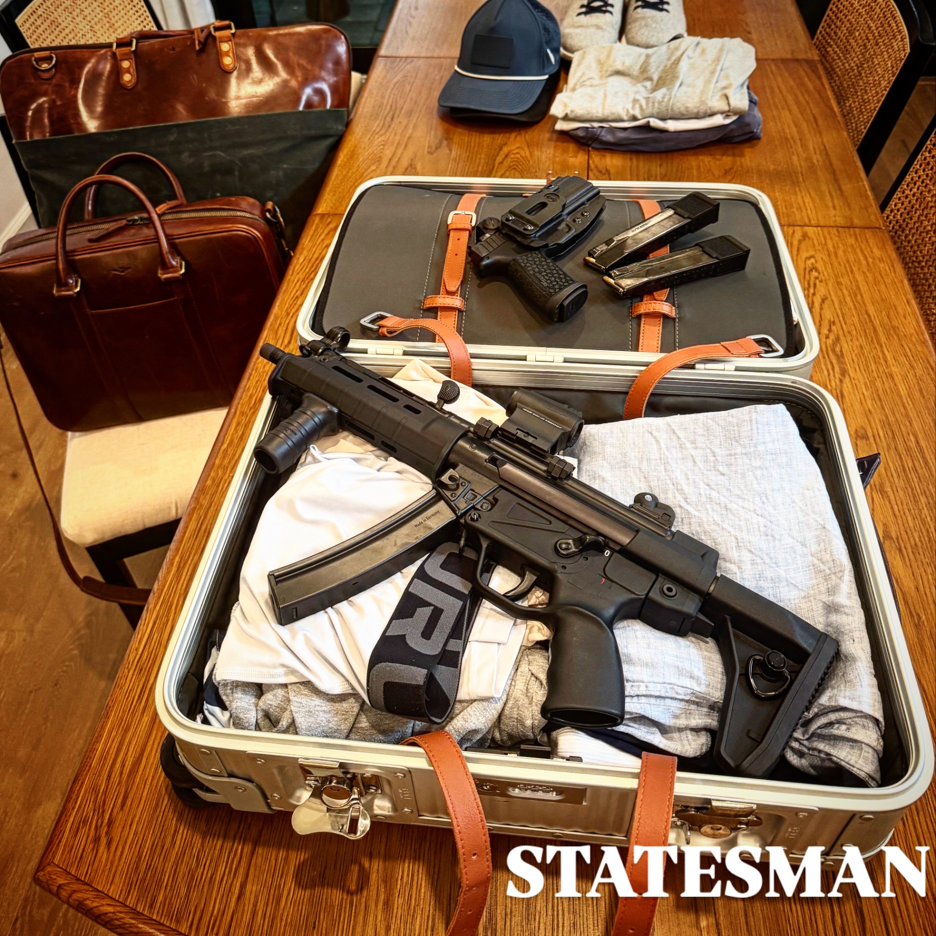 Suppressed HK MP5 clone and Sig pistol staged in an open luggage case with leather bags