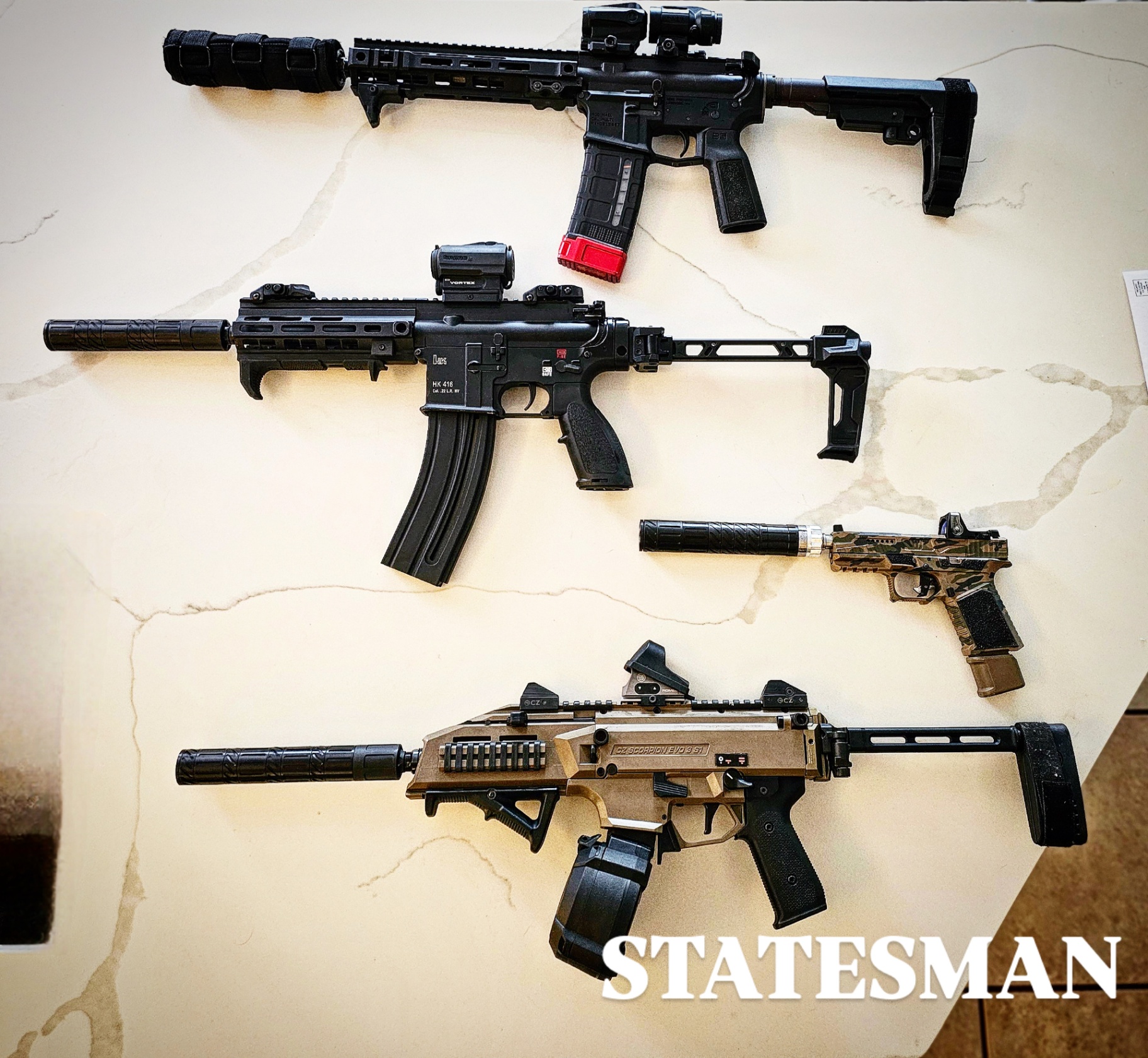 Suppressed rifles and pistols staged on marble